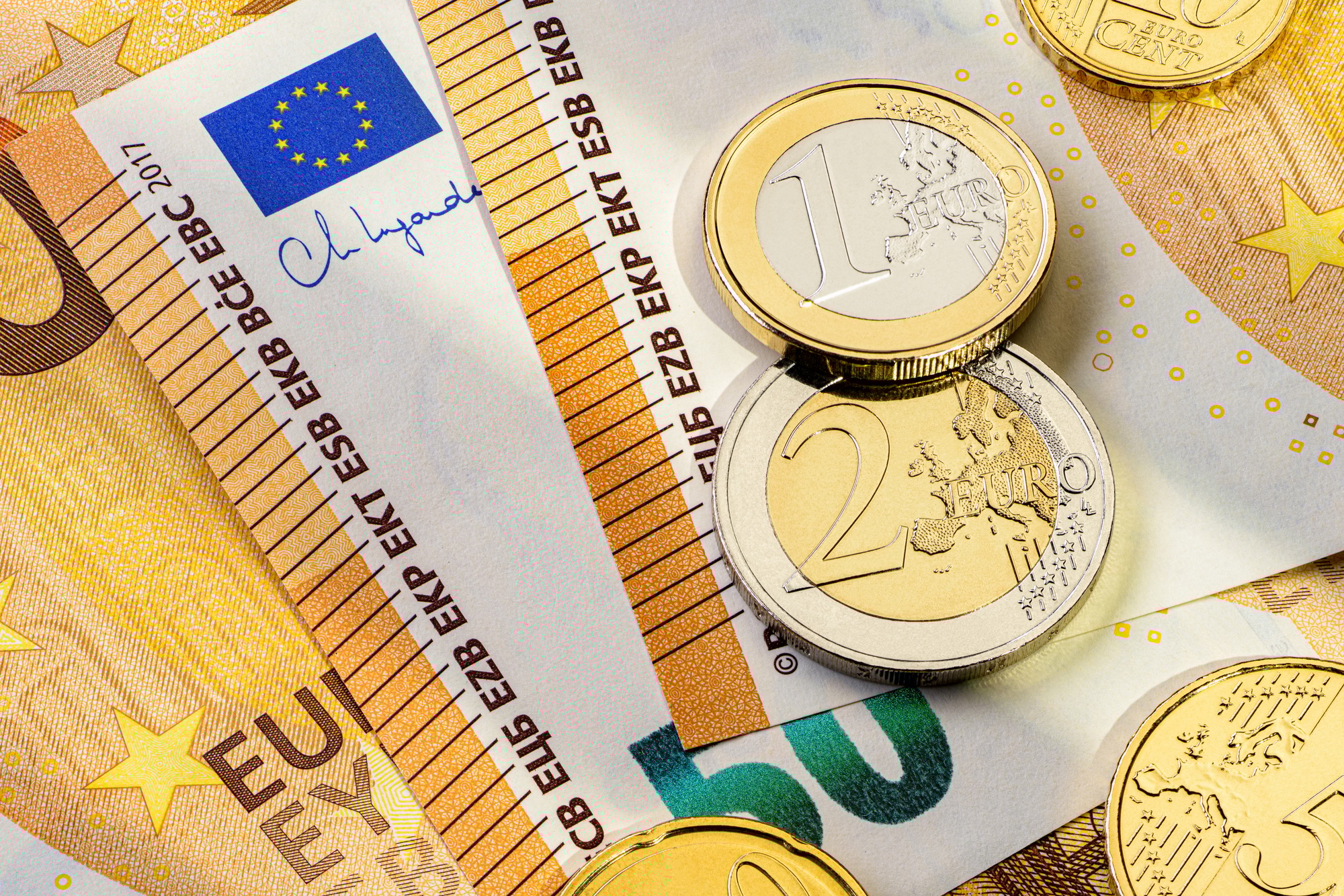 Fifty euro banknotes and different coins on a flat surface.
