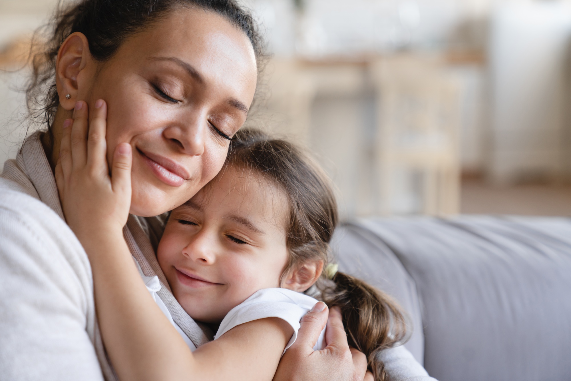 Mother and daughter embracing with eyes closed, expressing love and care.Happy Mother`s day!